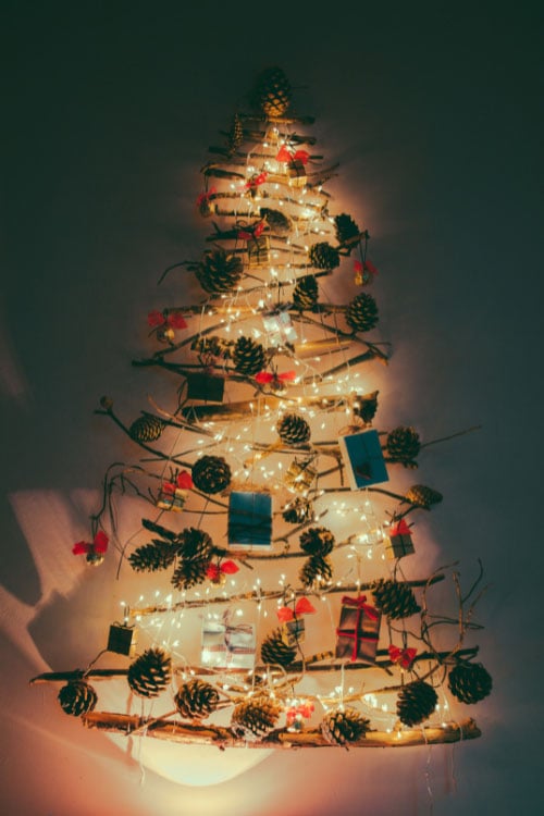 Arrange string lights in the shape of a tree on an open wall